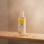 Burt's Bees Breakout Defense Foaming Wash on light-wood bath shelf with misty fresh shower background