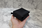 Compactly folded black nylon travel pouch resting in hand demonstrating lightweight packable design