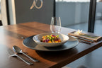 Contemporary dinner plate arrangement featuring polished silver mirror-finish cutlery in warm evening light