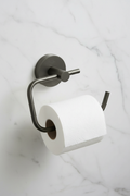 Grohe Essentials Hard Graphite toilet paper holder with toilet paper roll mounted on white marble bathroom wall