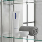 ZO Medical Foamacleanse on glass bathroom shelf with gray towel and porcelain bowl
