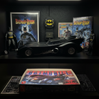 AMT 1/25 scale Batman and Robin Batmobile model kit assembled and displayed on collector shelf alongside Batman memorabilia and DC Comics items