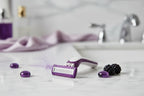 Premium women's razor cartridges resting on a white marble vanity in soft light with purple and berry color accents
