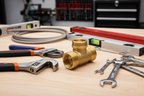 Professional plumbing tools laid next to a new brass valve body on a clean workshop surface