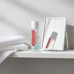 Rodan + Fields ESSENTIALS eye makeup remover bottle on a bright bathroom shelf beside a mirror and folded white towel