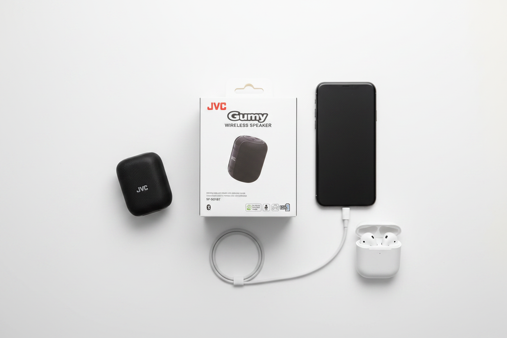 JVC Gumy SP-SG1BT wireless Bluetooth speaker black tech flat lay with phone earbuds and charging cable on white surface – More4less Outlet