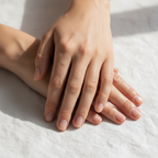 Close-up of smooth, well-moisturized hands resting on white linen, dewy hydrated skin