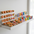 Tiny miniature food collectibles displayed on a white shelf alongside other small collectible toys