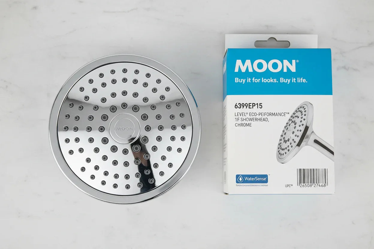 Studio macro of chrome showerhead face-up on white marble showing precise nozzle distribution