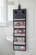 Mary Kay Discover What You Love roll-up travel bag hanging on a bathroom door hook, compartments filled with makeup and beauty products.