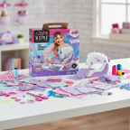 Cool Maker Stitch N Style Fashion Studio sewing machine by Spin Master on a bright crafting desk with colorful fabric swatches, thread spools, and fashion accessories – More4less Outlet