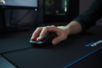 Hands gripping Corsair Raptor M3 black gaming mouse during FPS gameplay on ROCCAT Kanga mousepad in dark gaming room