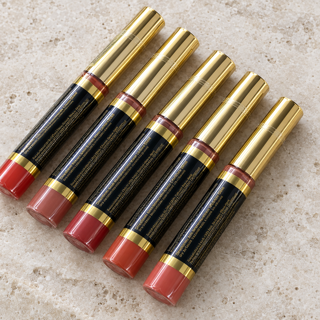Close detail of sealed black and gold LipSense lip color wands on pale stone