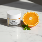 RoC Multi Correxion Revive + Glow Gel Cream jar on white marble with halved orange and green leaves.