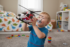 Young child playing with Maxx Action RH-1 911 rescue helicopter toy on bedroom floor