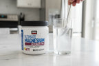 Force Factor Magnesium powder jar next to glass of water being mixed on marble kitchen counter