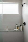 Rodan + Fields Body Micro-Dermabrasion on organized modern walk-in shower ledge with natural daylight