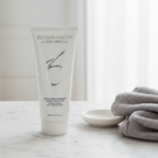 ZO Skin Health Exfoliating Cleanser 200mL silver tube on a white marble countertop with grey towel and ceramic dish
