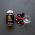 GNC Mega Men Gummy Multivitamin bottle on dark slate with mixed berries and water – More4less Outlet