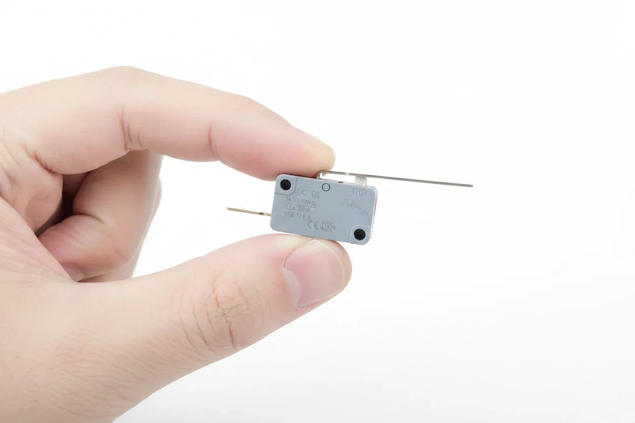 Hand holding a new gray OEM electrical microswitch component ready for appliance installation