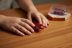 Child holding HEXBUG Fire Ant red micro robotic creature showing translucent body and internal mechanics