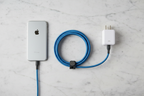 Belkin BoostCharge Pro Flex blue Lightning cable flat lay on marble with magnetic management strap, iPhone, and USB-A charger — More4less Outlet