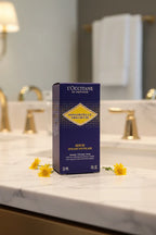 Dark blue luxury skincare serum box resting elegantly on a bright white marble vanity