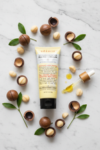 Adamia hand cream flat lay with macadamia nuts green leaves and oil dropper