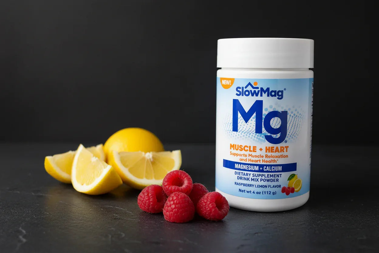 SlowMag Mg powder jar next to fresh sliced lemon and raspberries on dark slate surface