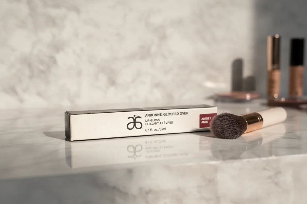 Arbonne Glossed Over Lip Gloss Anise on marble makeup vanity soft natural morning light lifestyle