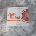 Close detail of the Kara Beauty Holy Balm grapefruit cleansing balm box on a neutral stone surface