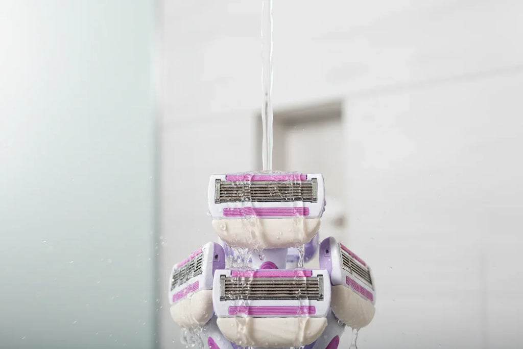 Close-up of water splashing over high-quality 5-blade women's razor cartridges in a bright shower setting