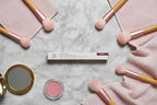 Arbonne Matte and Shine Lip Duo Bloom flat lay on slate surface with pastel towels and cosmetic brushes