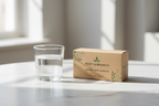 Glass of water beside Salus Floradix iron vitamin supplement box on white marble surface