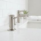 Professional hardware install staging showing a sink-deck mounted Kohler liquid soap dispenser in brushed stainless