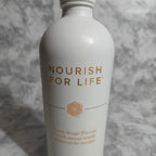 Close-up detail of premium white aluminum health tonic bottle with gold typography on marble counter, shallow depth of field