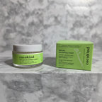 Modern clean skincare composition showcasing green label moisturizer cream jar and box on soft white marble surface