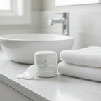 Organized bathroom vanity with exfoliating face pads and a folded soft white towel beside a white skincare canister