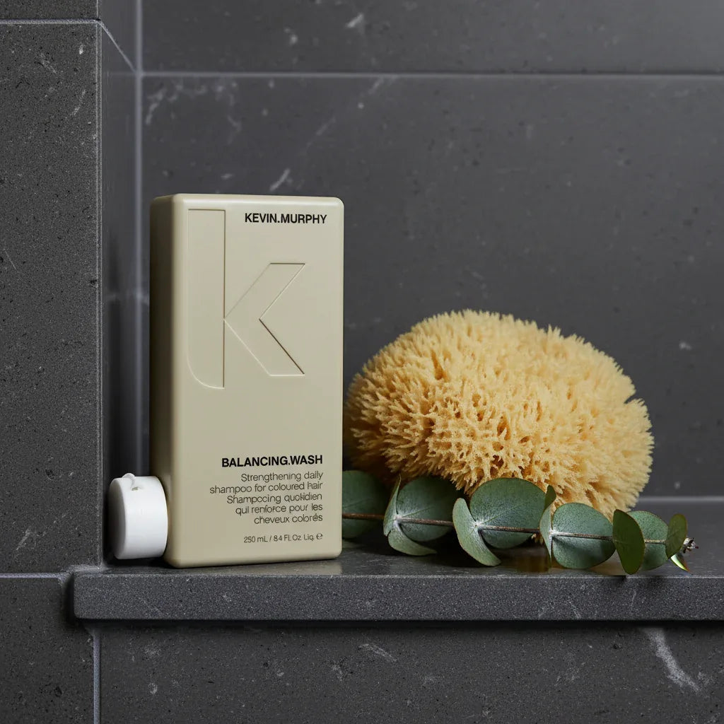 Kevin Murphy Balancing.Wash on dark slate-gray quartz shower niche with sea sponge and eucalyptus sprig