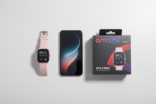Amazfit GTS 4 Mini smartwatch Flamingo Pink on white desk flat lay with phone and retail box – More4less Outlet