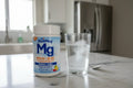 SlowMag Mg powder jar next to effervescent glass of water on marble kitchen island