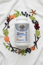 Garden of Life Sport Organic Plant Protein vanilla flat lay on white background with peas lentils cranberries and vanilla beans