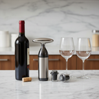 OXO SoftWorks Vacuum Wine Preserver stainless steel pump and stoppers displayed beside open red wine bottle and glasses on marble countertop