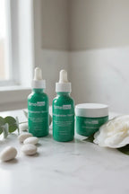 Professional health and beauty display showing curated minimalist green glass serum bottles on clean white marble surfaces