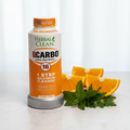Herbal Clean QCarbo 16 orange bottle on white marble beside fresh orange slices and green herbs – More4less Outlet