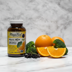 MegaFood Men's 40+ One Daily amber glass bottle beside fresh organic oranges broccoli and elderberries on white marble – More4less Outlet