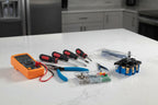 Appliance repair tools arranged on a clean white granite kitchen island