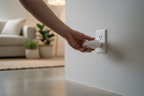 Homeowner plugging a white device into a wall outlet in a clean modern home