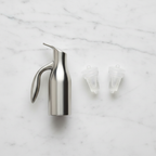 OXO SoftWorks Vacuum Wine Preserver 3-piece set flat lay — stainless steel pump and two clear silicone stoppers on white marble