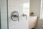 Modern minimalist bathroom renovation detail showing chrome shower trim hardware on white subway tile